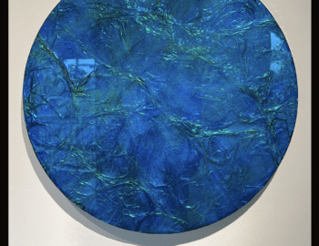 A circular artwork titled "Mystic Water" (2024) by John Niederhauser, created with mixed media and resin, measuring 18 inches in diameter. The piece features a textured blue and green surface.